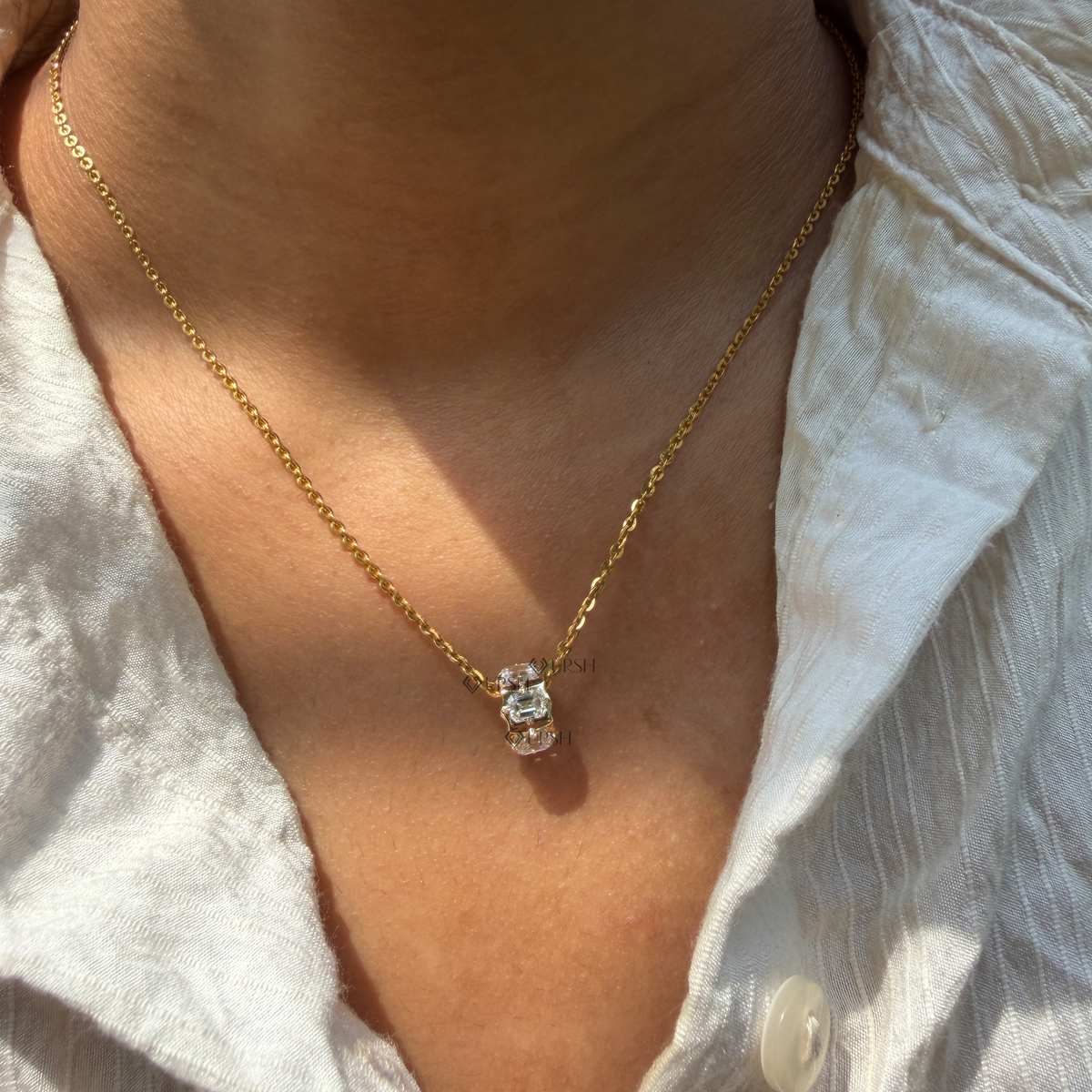 Daylight angle view of yellow gold emerald cut diamond barrel bead pendant chain worn on neck