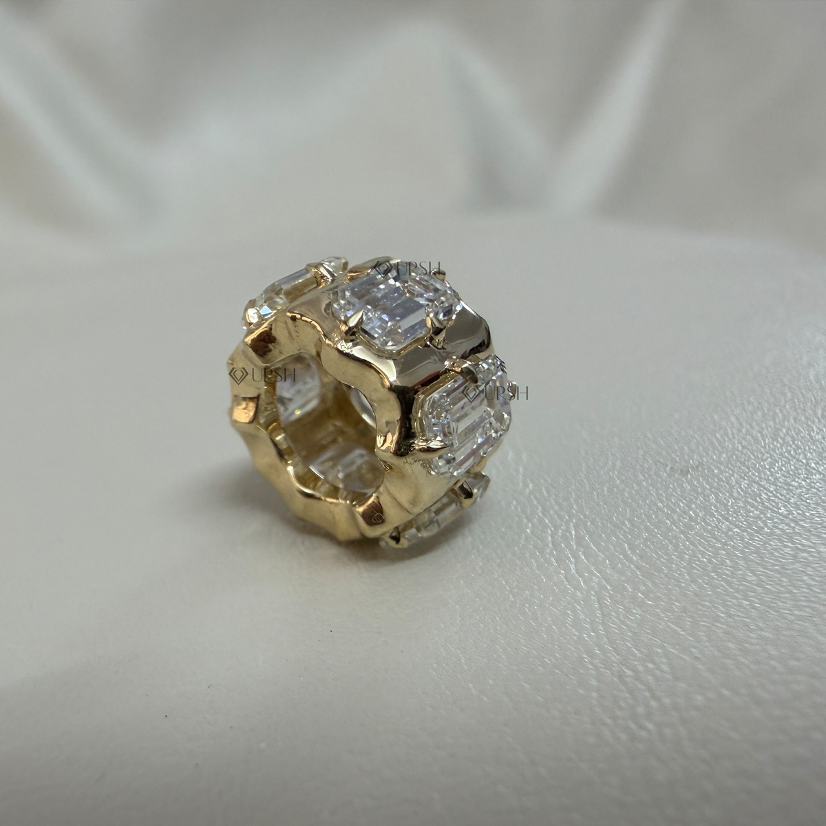 Solid yellow gold emerald cut diamond rondelle bead charm resting flat on neutral surface