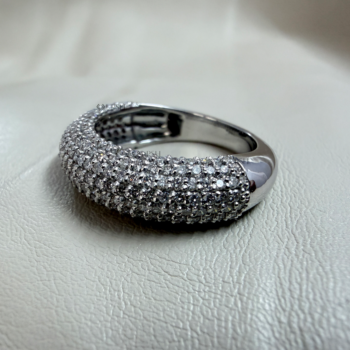 Studio view of white gold pavé dome ring highlighting smooth polished shank and curved stone surface
