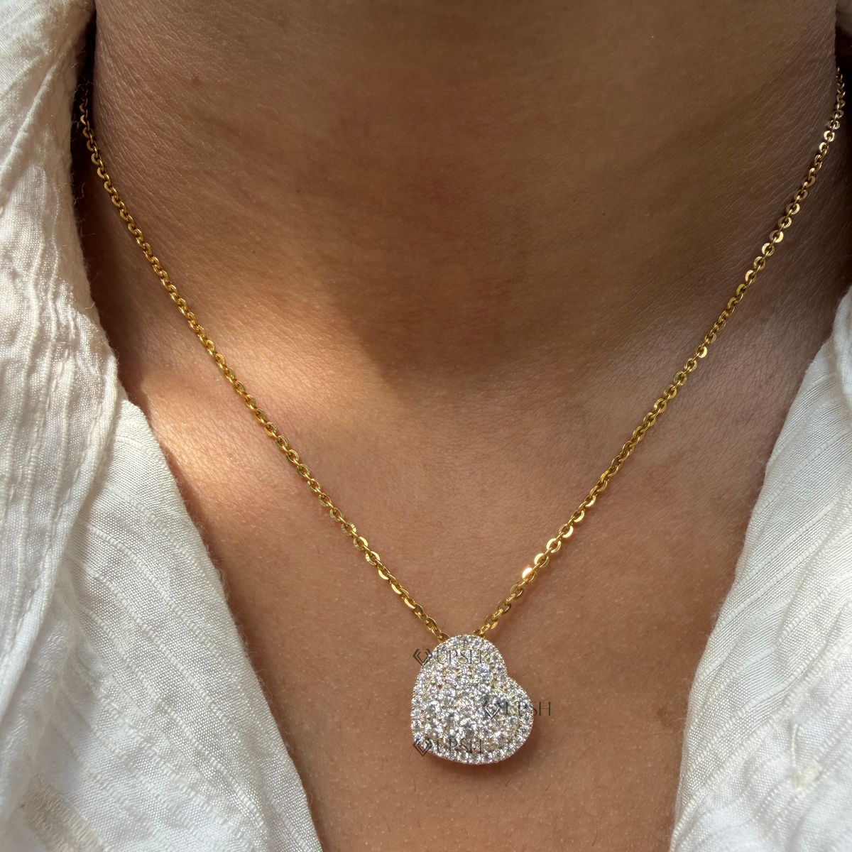 Daylight angle view of yellow gold pavé diamond heart pendant chain worn on neck