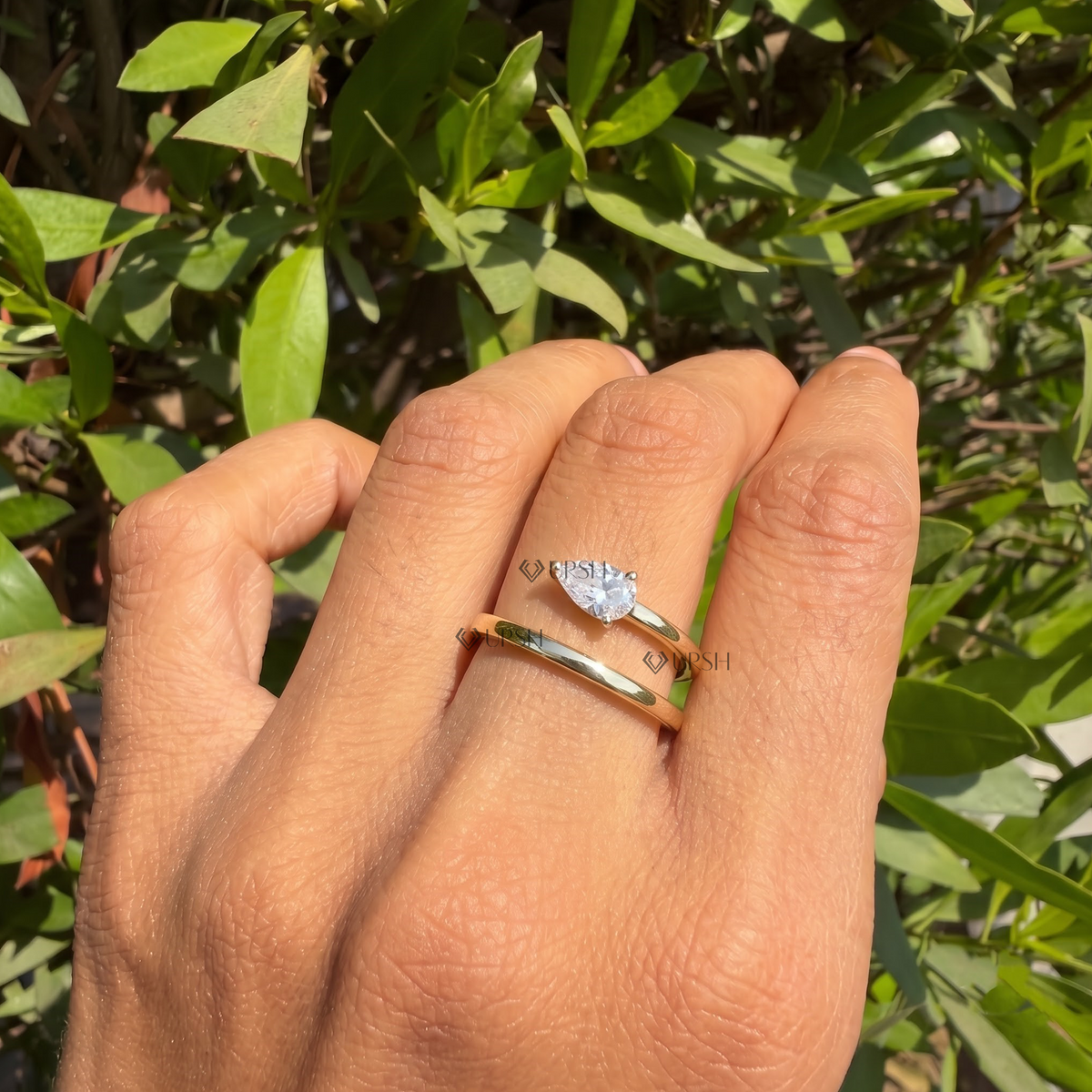 Detailed daylight macro close-up of prong-set pear lab diamond on polished spiral coil band held between fingers