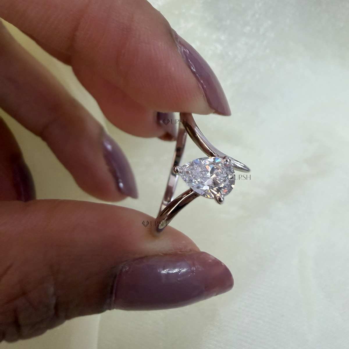 Close-up holding white gold curved v band ring showing open basket and delicate diamond orientation