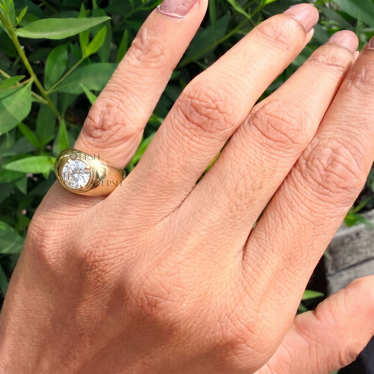 Yellow gold chunky dome solitaire ring worn against natural garden greenery