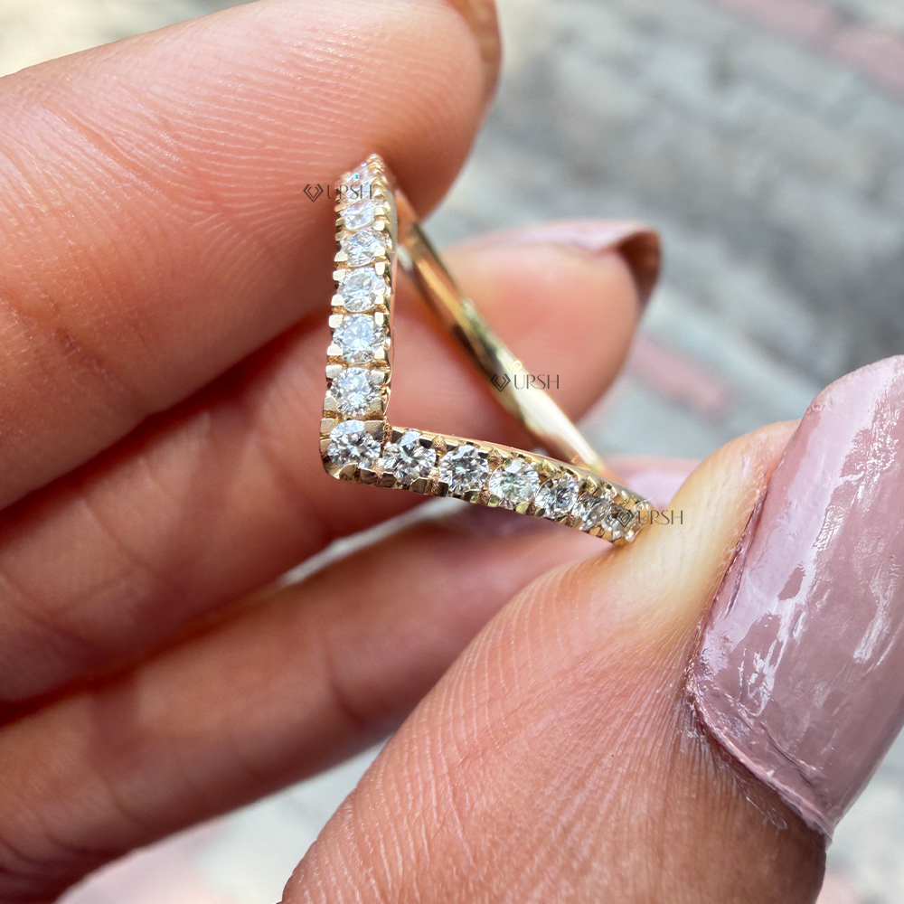 Close-up holding solid gold curved chevron ring showing v-point depth and pavé prongs