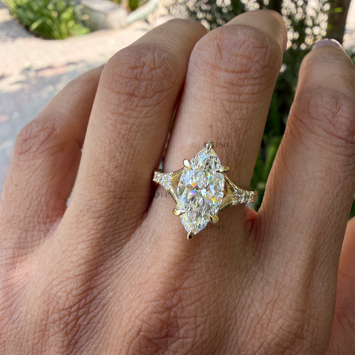 Elongated marquise diamond vintage engagement ring worn on finger in natural sunlight