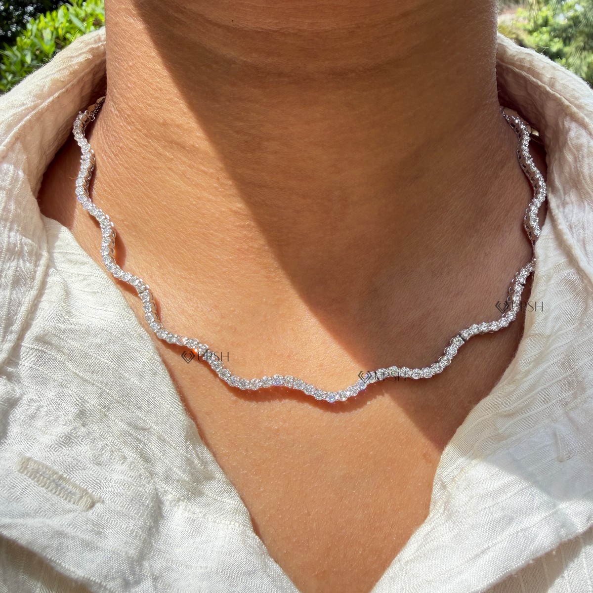 Daylight angle view of white gold wavy diamond tennis chain necklace worn gracefully on neck