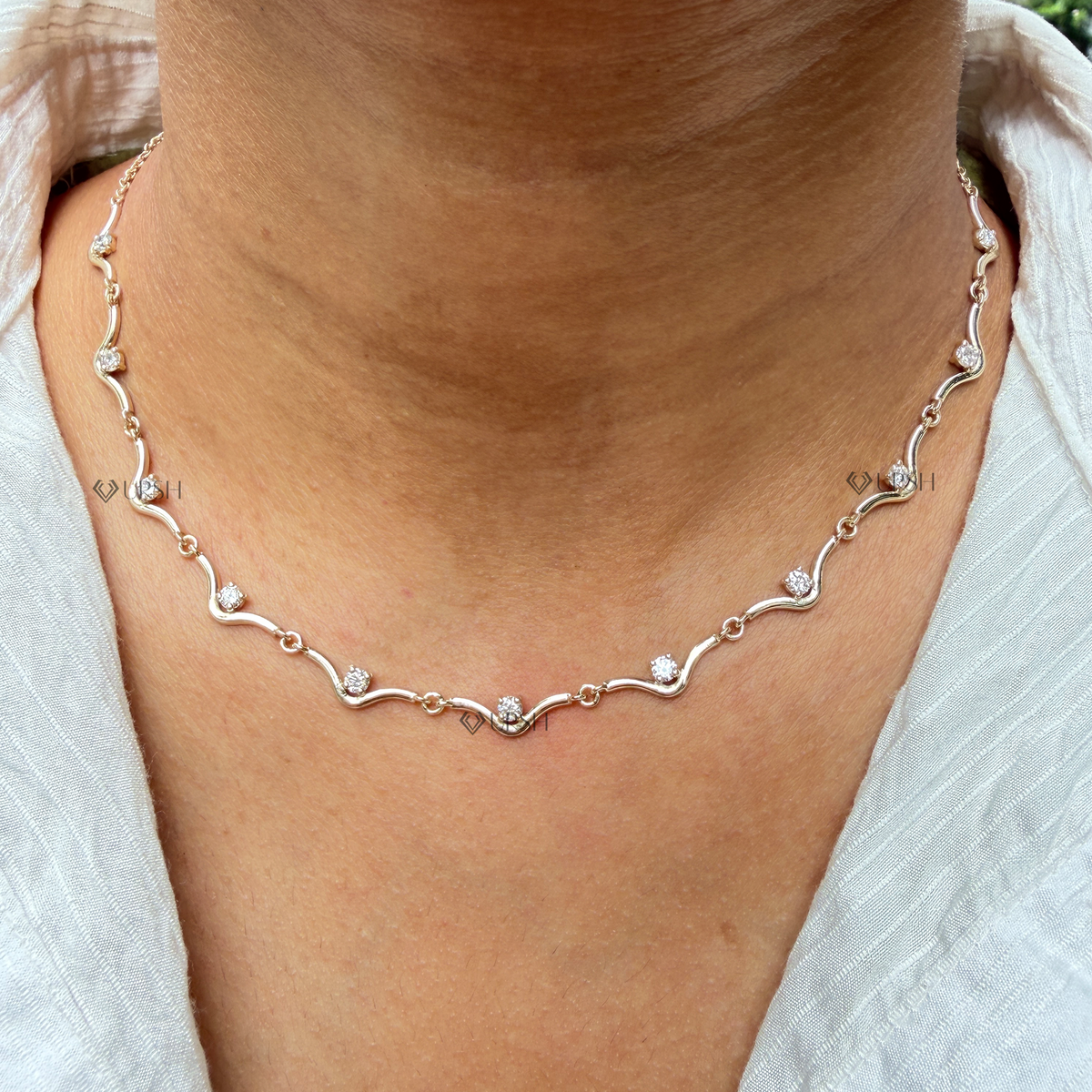 Daylight perspective of yellow gold wavy link diamond station chain worn along collarbone