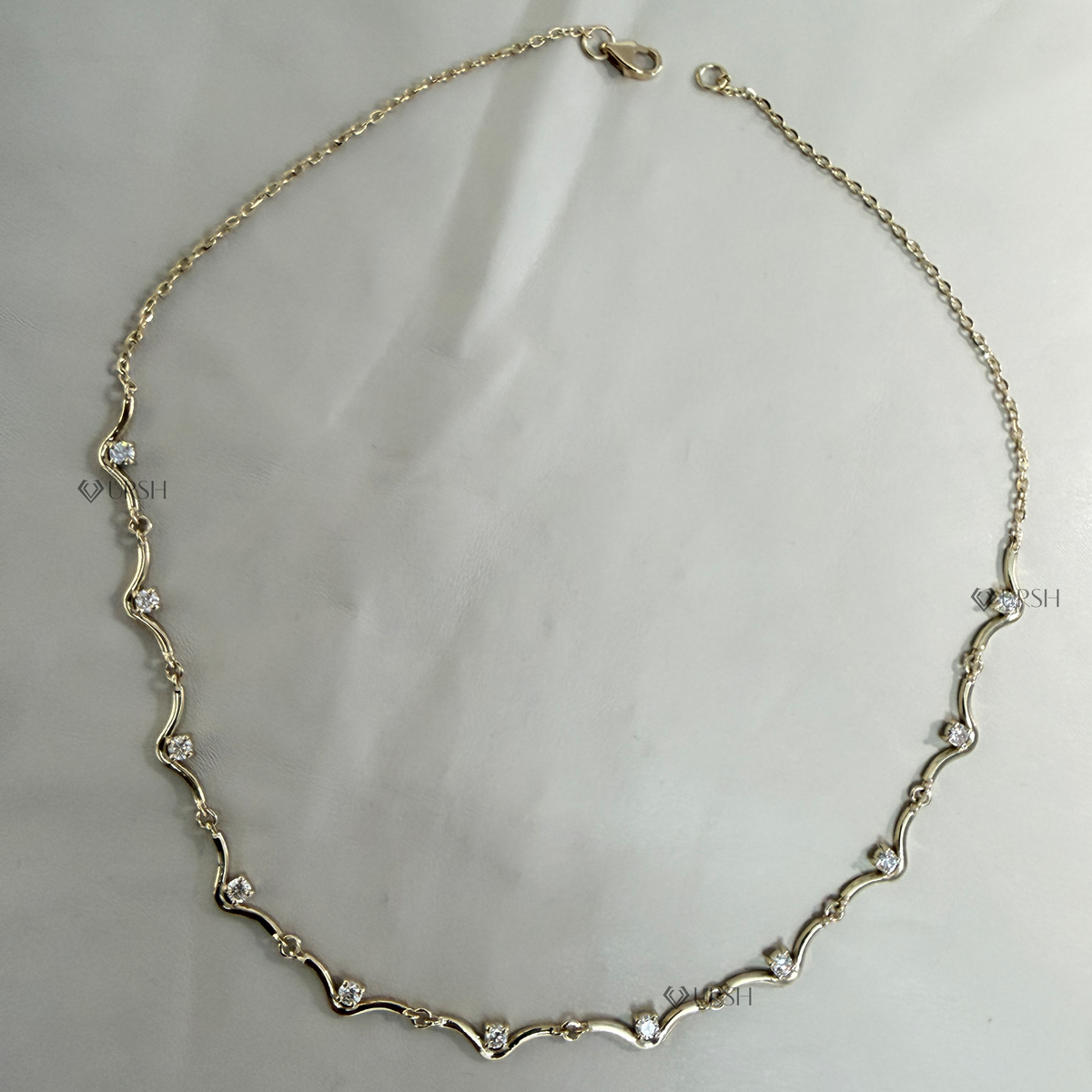 Solid white gold wavy link diamond station chain necklace laid flat on neutral background