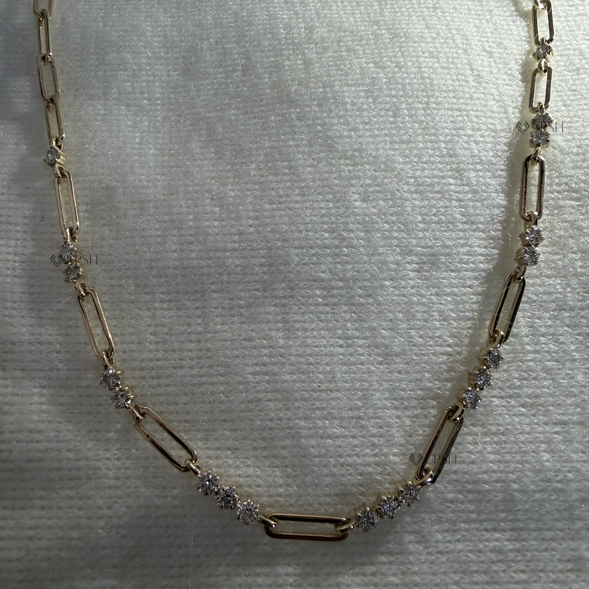 Solid white gold alternating diamond station paperclip chain necklace laid flat on neutral background