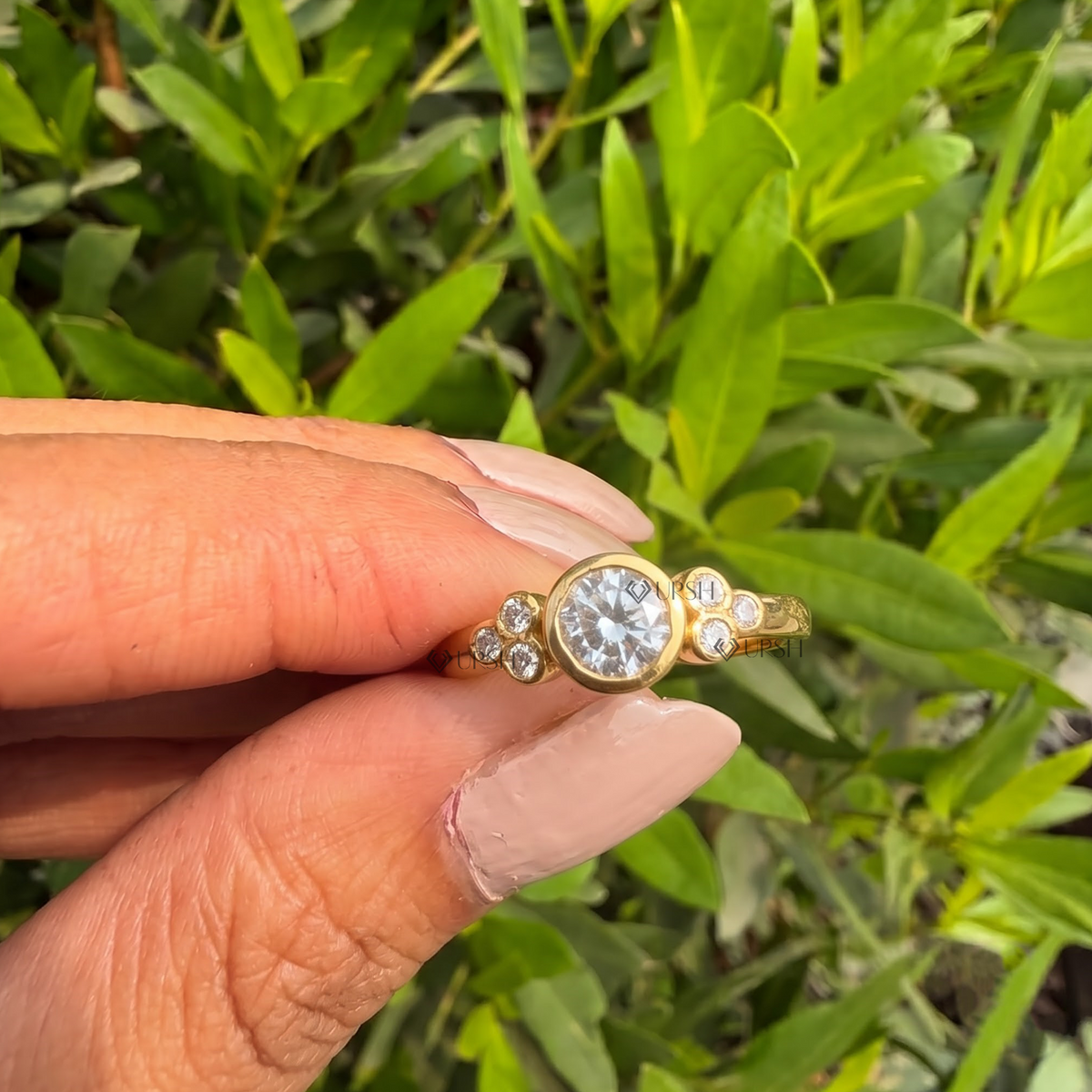 Detailed daylight close-up holding yellow gold bezel cluster ring to display smooth flush bezels