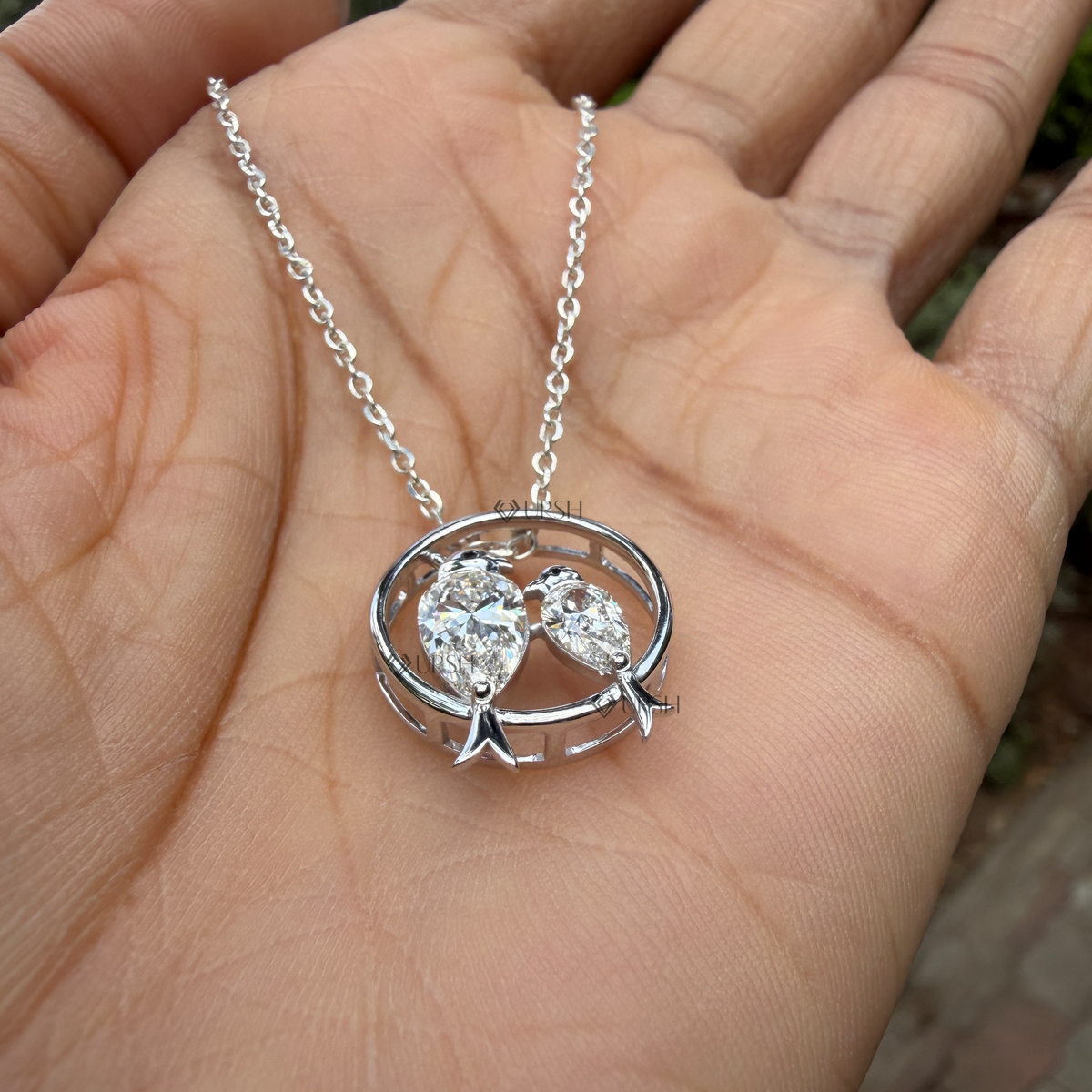 Detailed hand model view of solid white gold love birds diamond pendant held gracefully