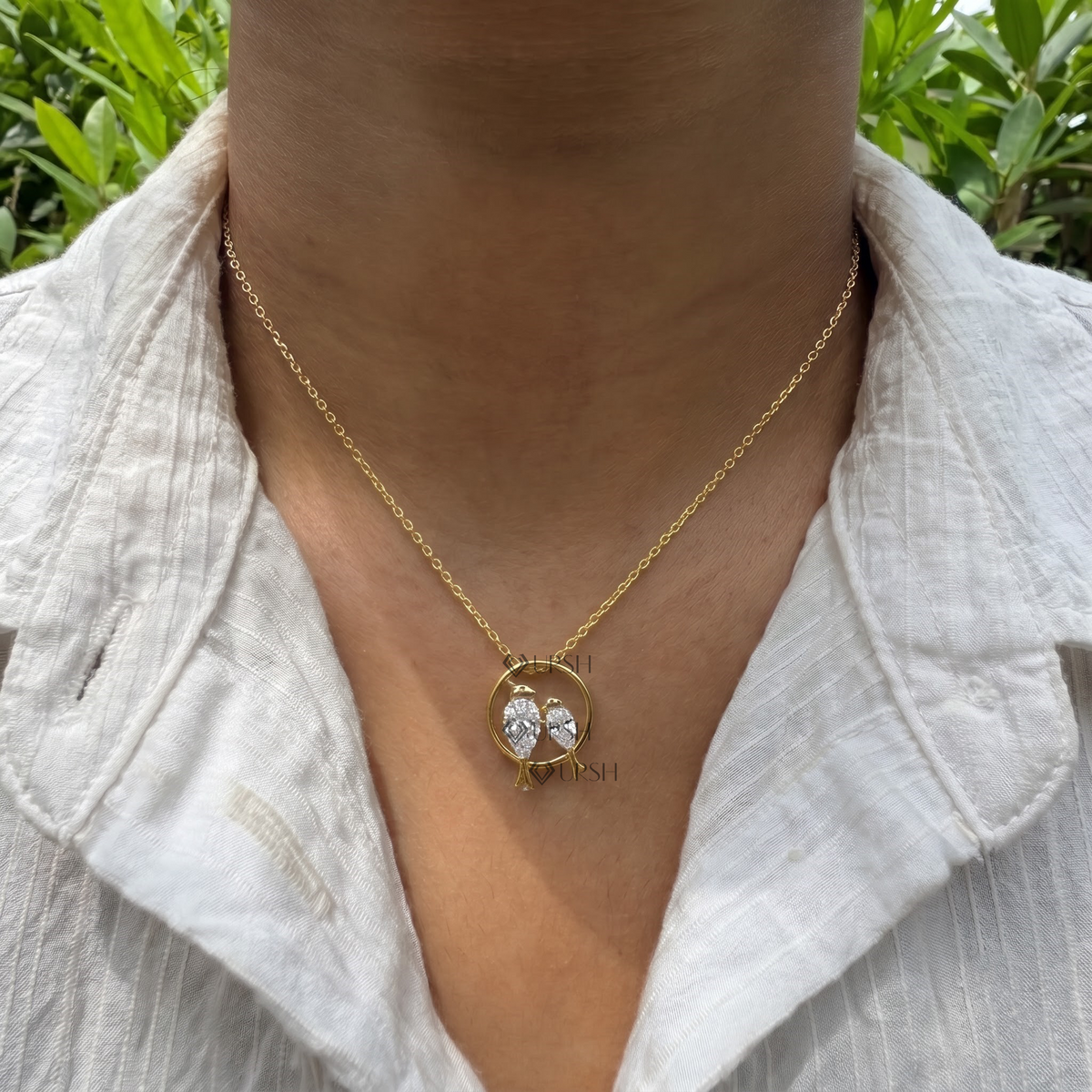 Daylight angle view of yellow gold love birds pendant chain worn along collarbone