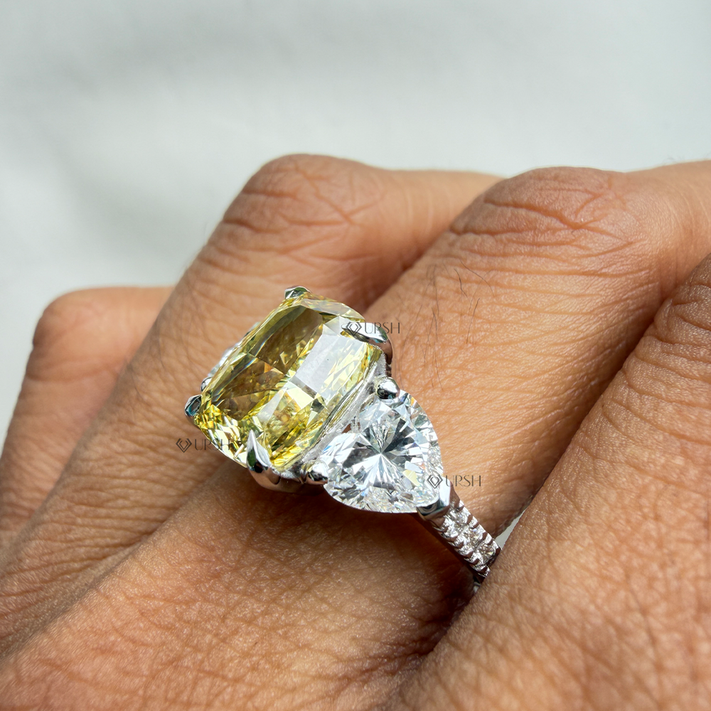 Detailed daylight view of canary yellow cushion lab diamond and heart-cut side stones worn on hand