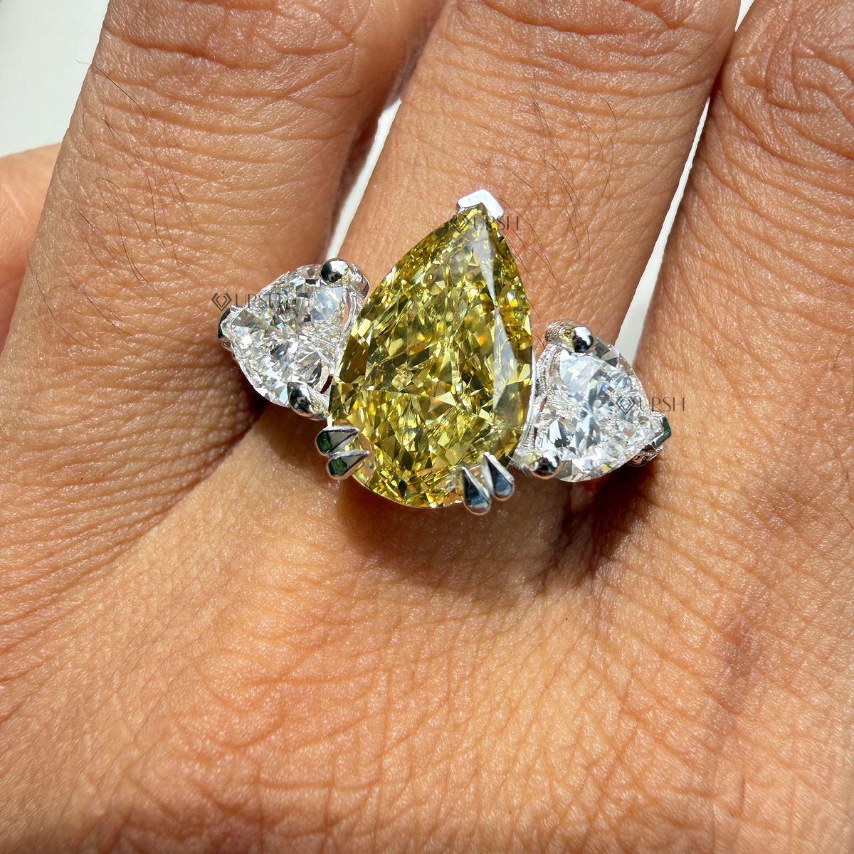 Stunning yellow pear diamond trilogy ring styled gracefully on hand in natural daylight