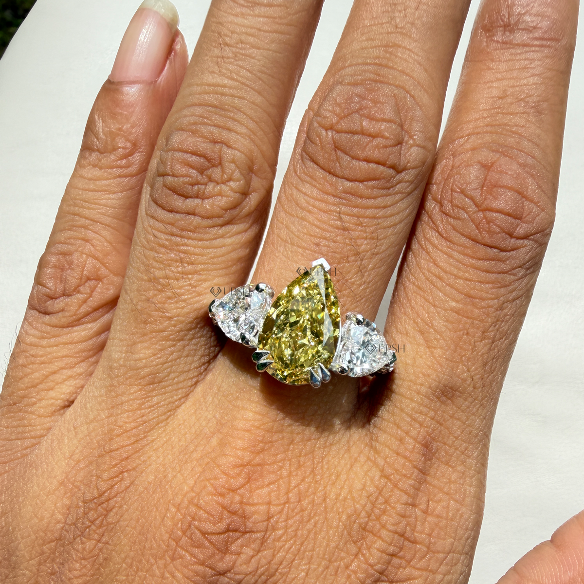 Impressive finger coverage and brilliance of three-stone yellow pear and pavé ring worn outdoors