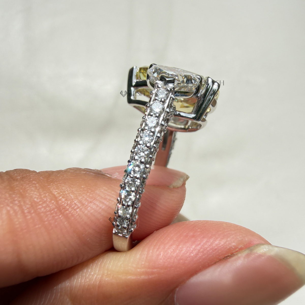 Holding two-tone yellow pear diamond ring showcasing side pear stone brilliance and shoulder pavé