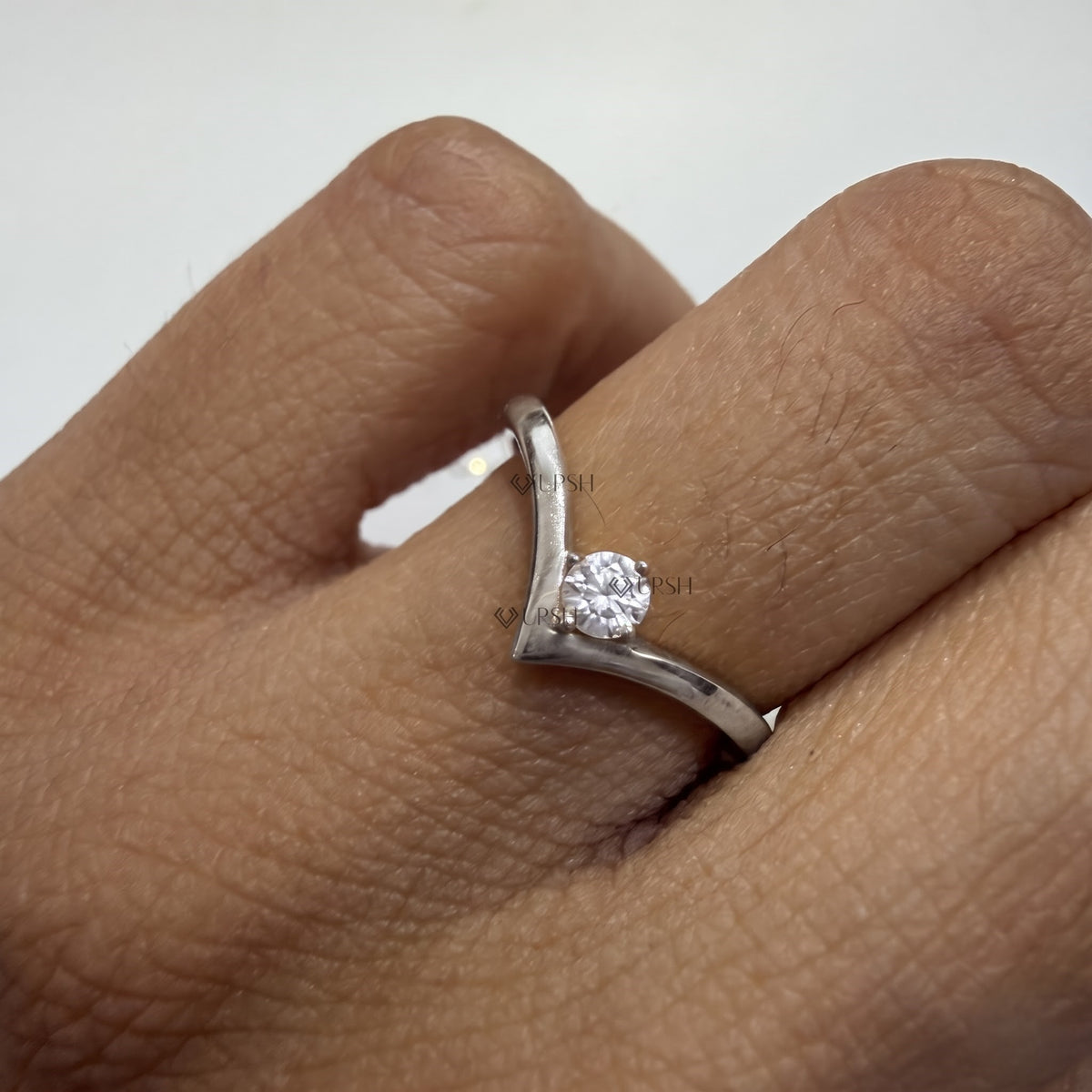 White gold wishbone diamond ring styled on hand showing off-center stone sparkle