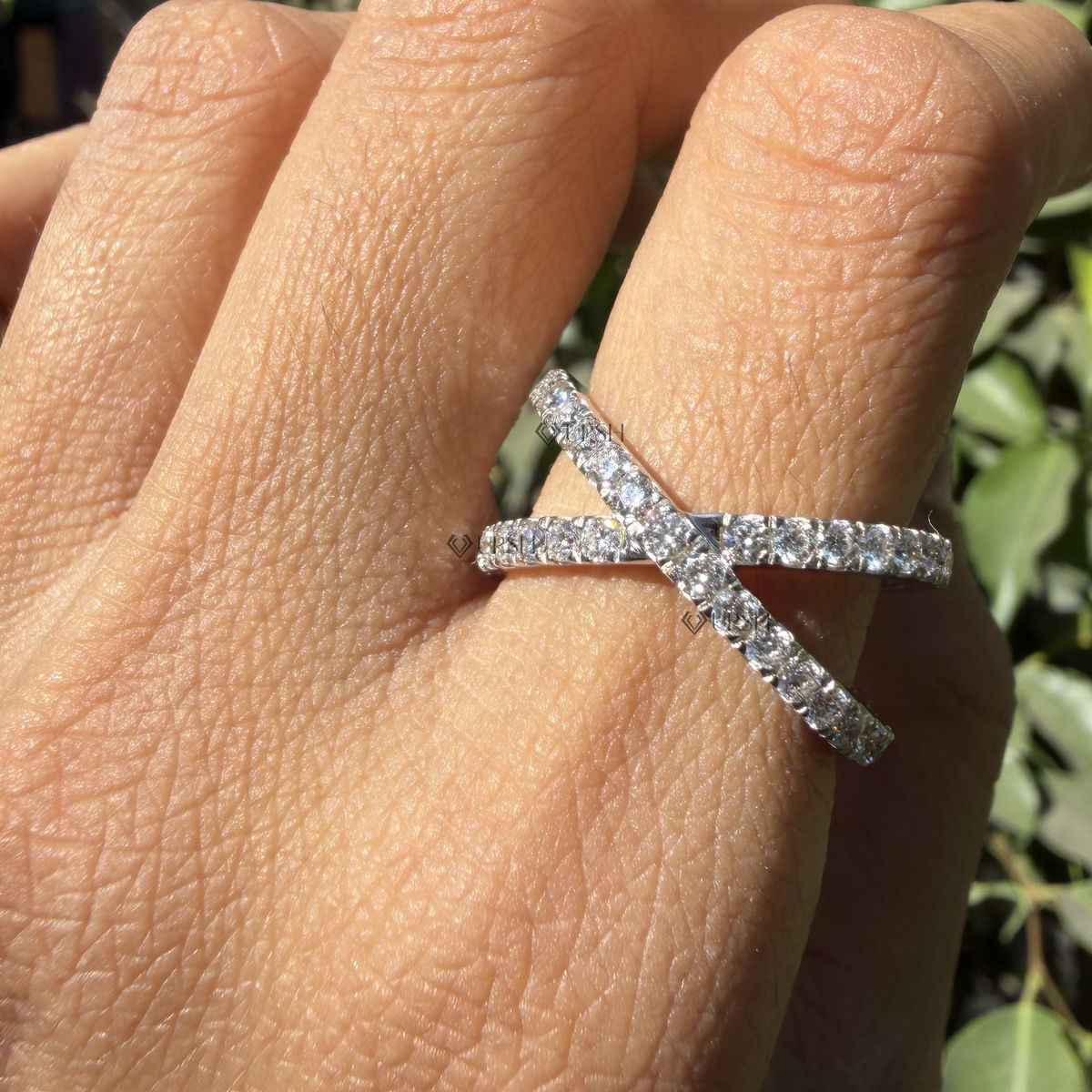 X-shaped crossing diamond statement ring styled gracefully on finger in natural daylight