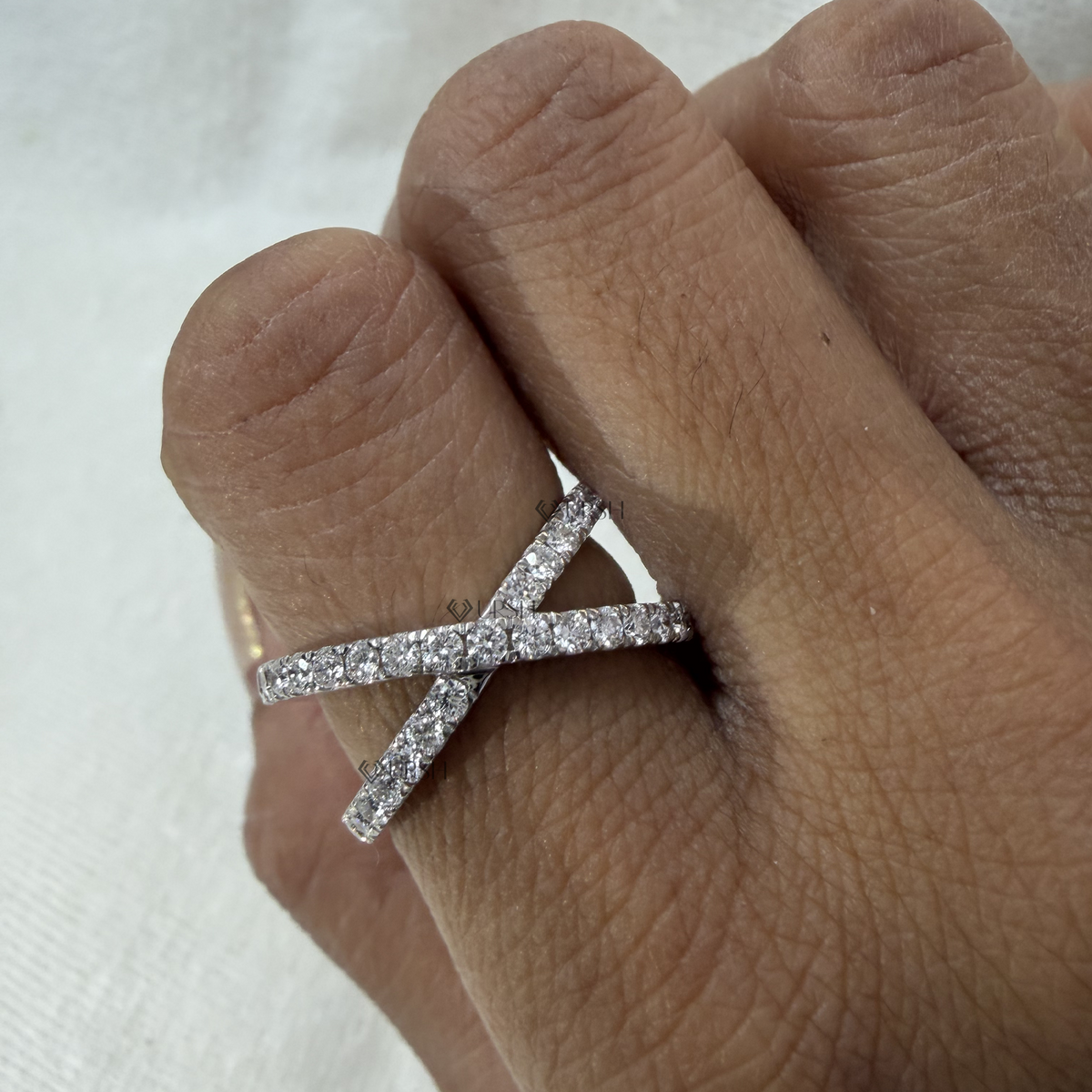 Detailed daylight close-up of micro-pavé intersecting tracks on criss-cross statement ring worn on finger