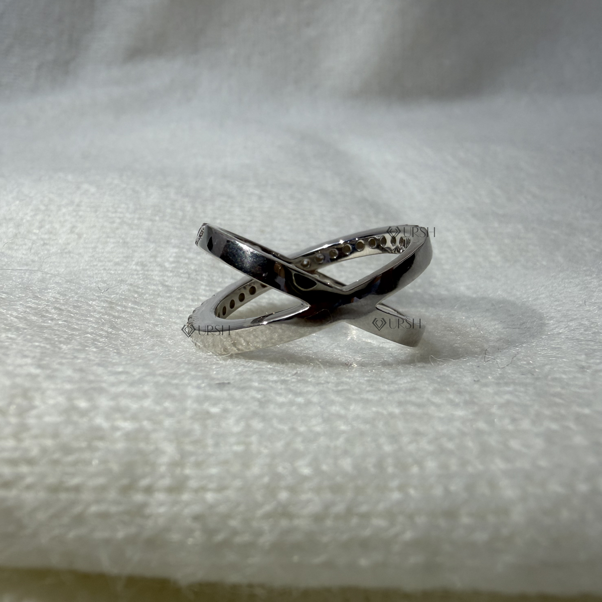 Studio angle of white gold X-shaped ring displaying polished crossover junction and mirror finish