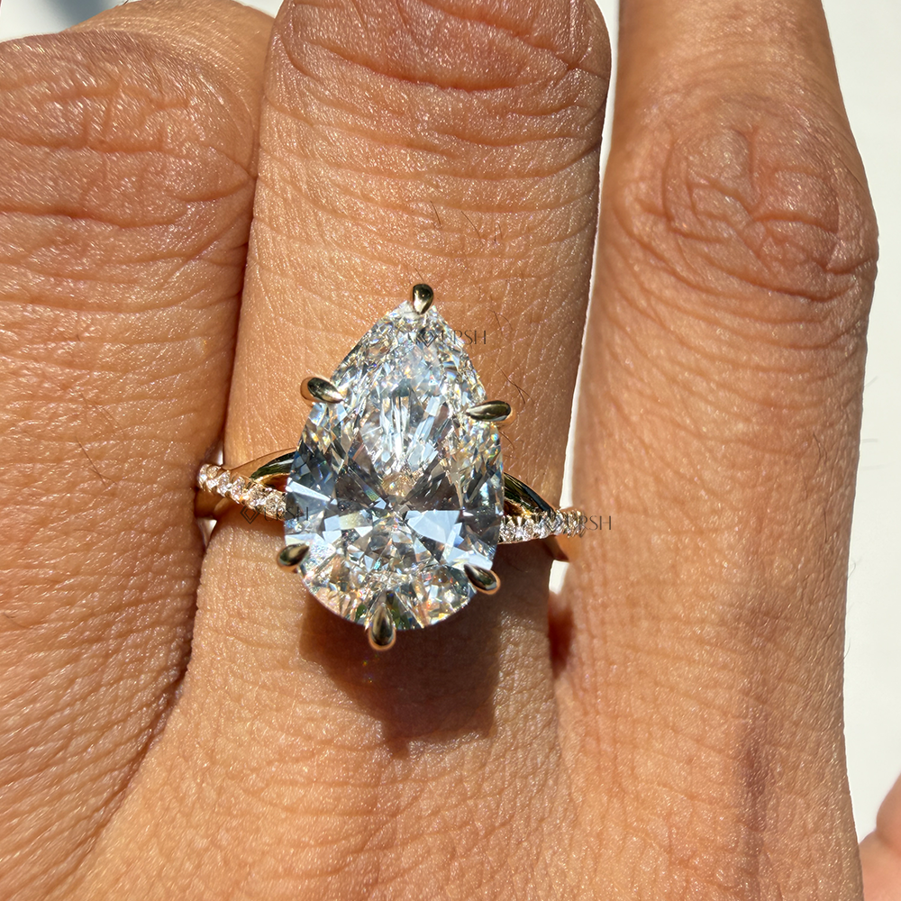 Detailed daylight sparkle and finger coverage of pear shape lab diamond on twisted pavé gold band