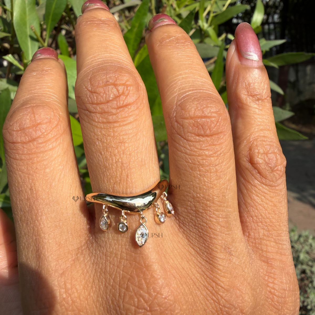 Close-up view of solid gold contoured band highlighting bezel marquise pear and round diamond dangles