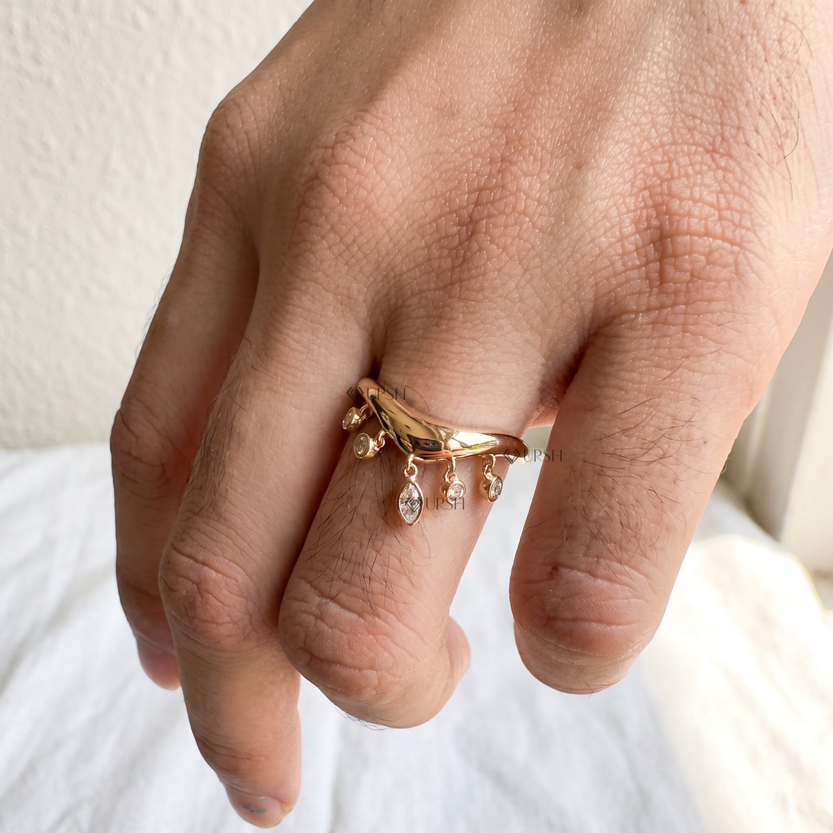 Frontal product shot of solid yellow gold curved ring displaying five graduated diamond drop charms