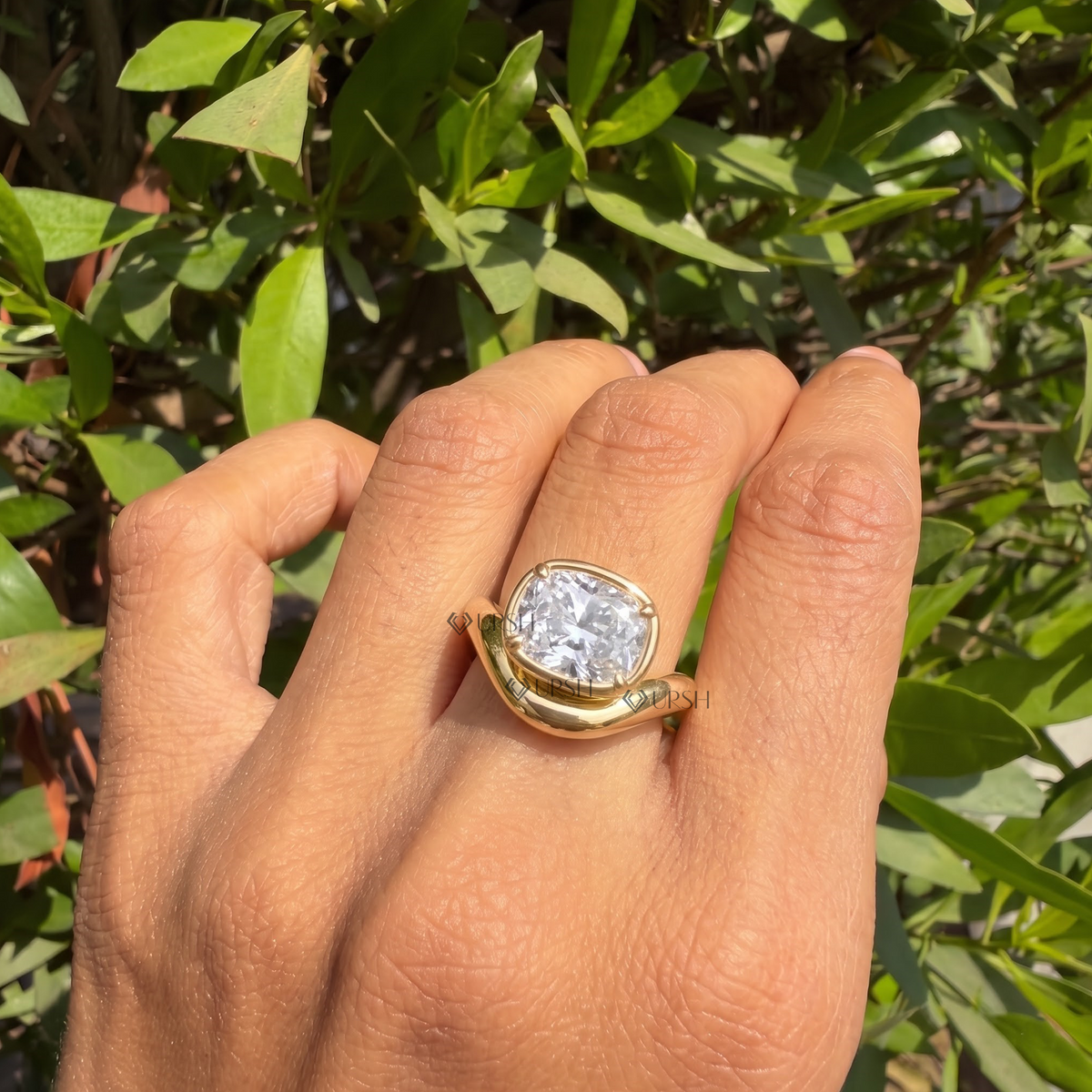 Bezel-set cushion cut crossover statement ring styled gracefully on finger in natural daylight