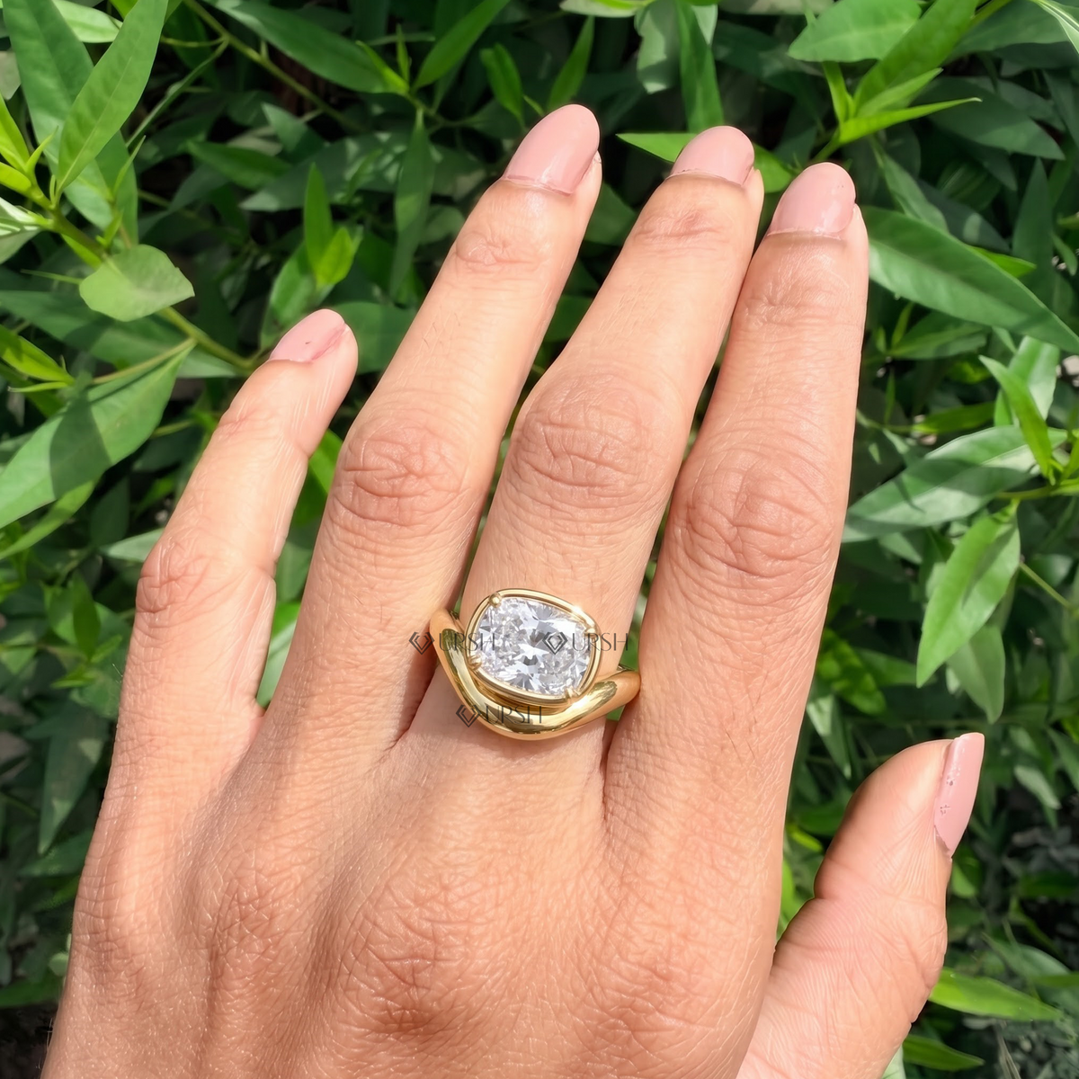Daylight perspective of wavy cushion statement ring worn against natural garden background