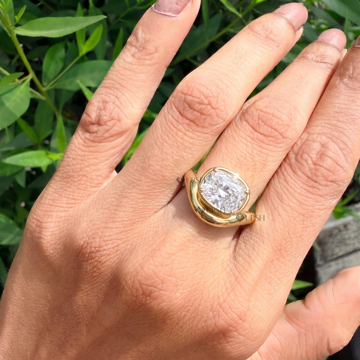 Close-up daylight angle view of yellow gold crossover statement ring worn on finger displaying low-profile bezel setting