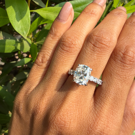 Cushion cut diamond engagement ring styled gracefully on finger in natural daylight