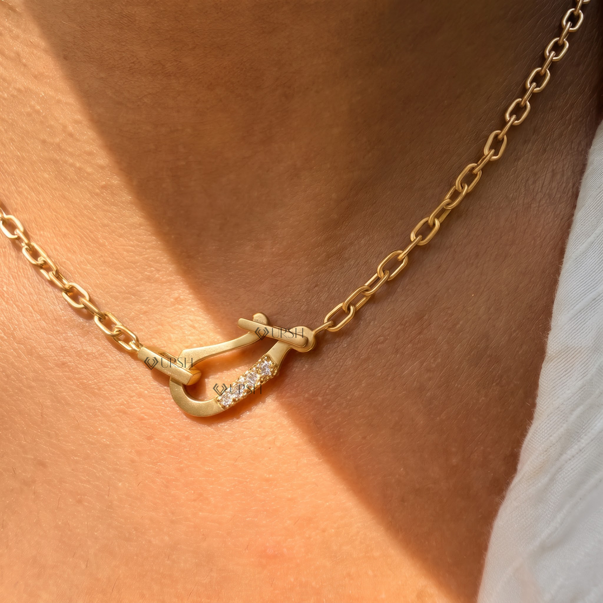 Daylight perspective of yellow gold carabiner lock centerpiece worn against collarbone