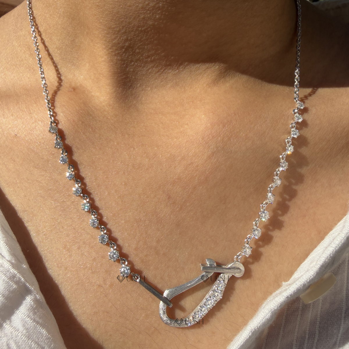 Daylight perspective of white gold carabiner hook diamond station chain worn against neck