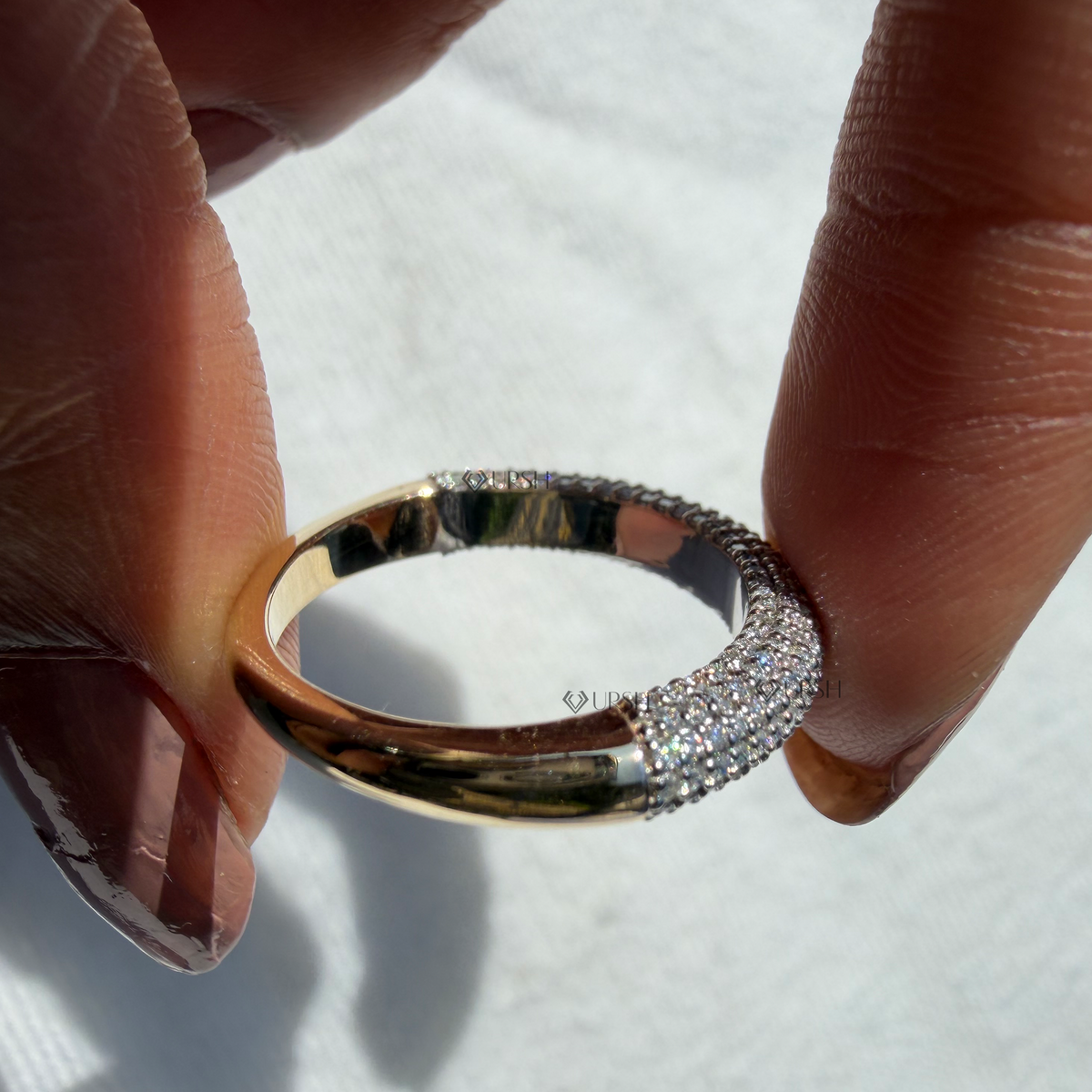 Detailed view of domed statement ring held up showing high-polish solid gold interior and tapered shank