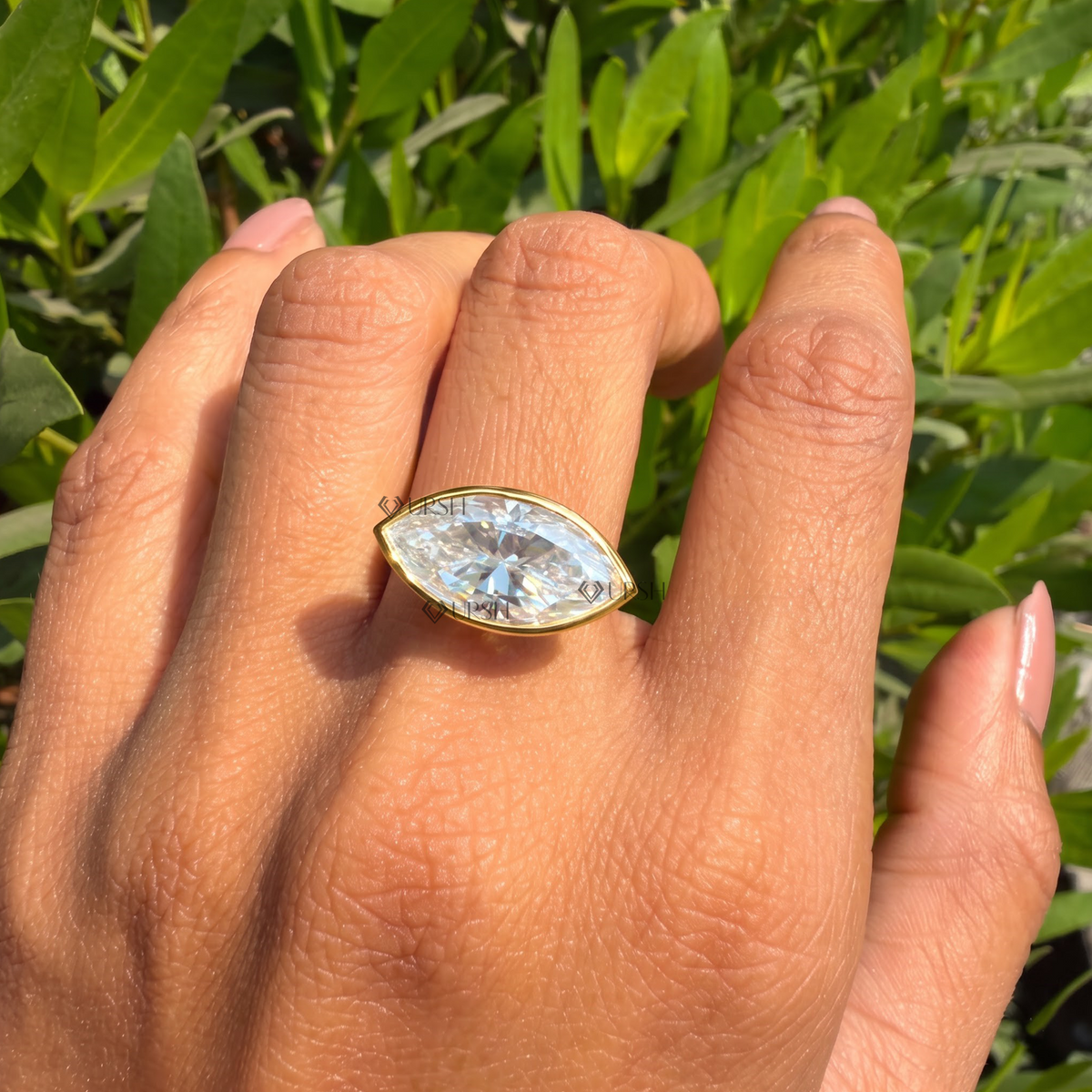 Bezel-set east-west marquise diamond ring styled gracefully horizontally on finger in natural daylight