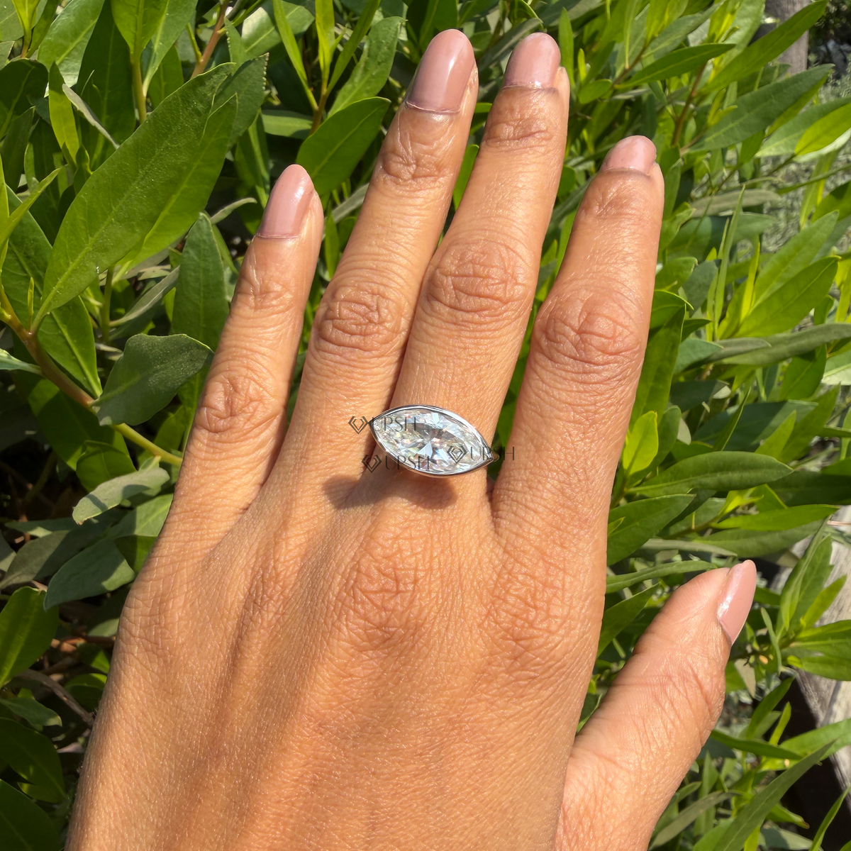 Close-up daylight angle view of horizontal marquise ring worn on finger displaying low-profile bezel setting