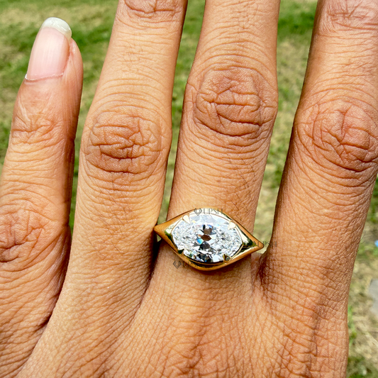 Horizontal marquise diamond gypsy bezel ring styled across finger in natural daylight