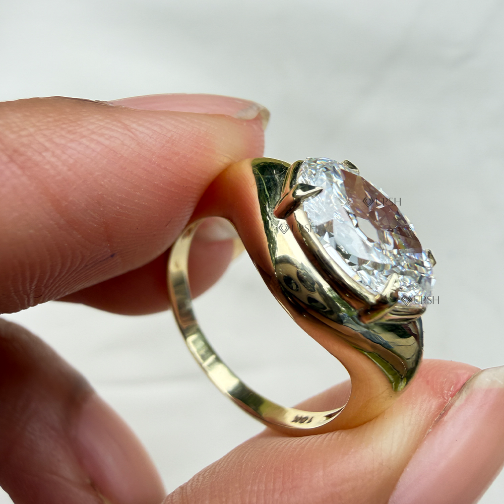 Holding solid gold east-west marquise ring displaying substantial tapered shoulders and mirror polish