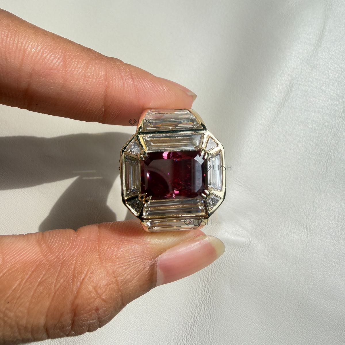 Detailed studio close-up of emerald-cut deep red ruby and channel-set baguette side stones
