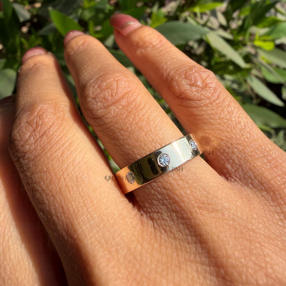 Wide diamond cigar band worn on ring finger against green garden backdrop