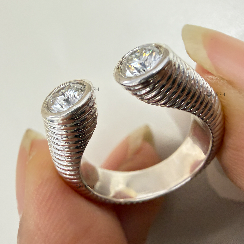 Close-up holding solid gold open gap ring displaying bezel diamond terminal ends and inner comfort band