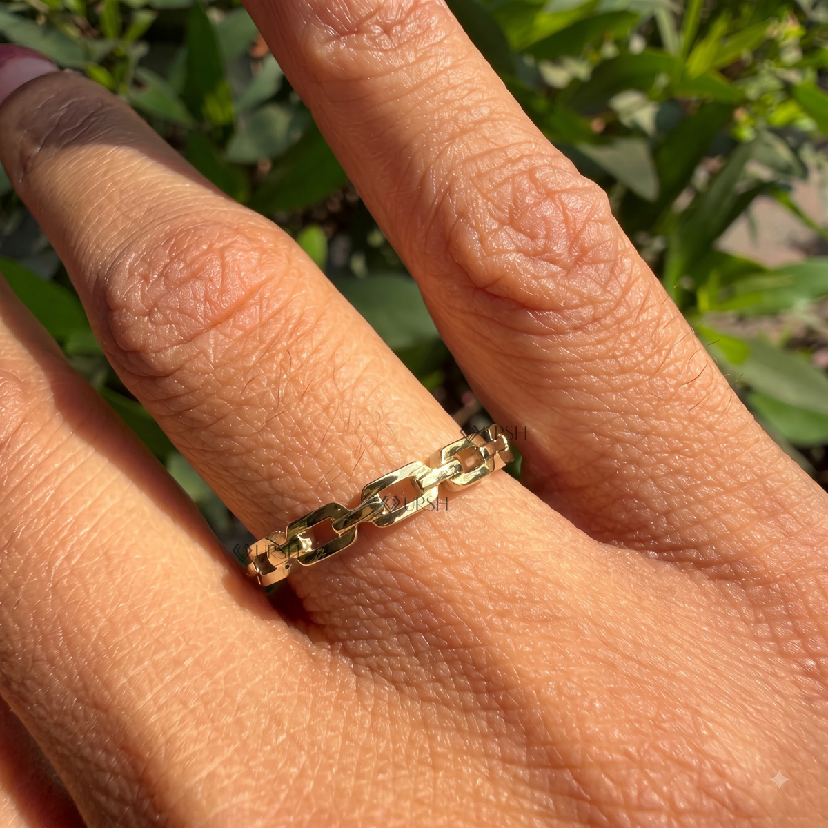 Daylight perspective of white gold chain link ring worn against natural background