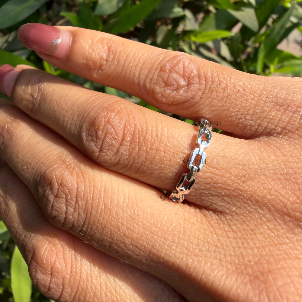 Detailed daylight macro close-up of polished white gold geometric link chain band worn on finger