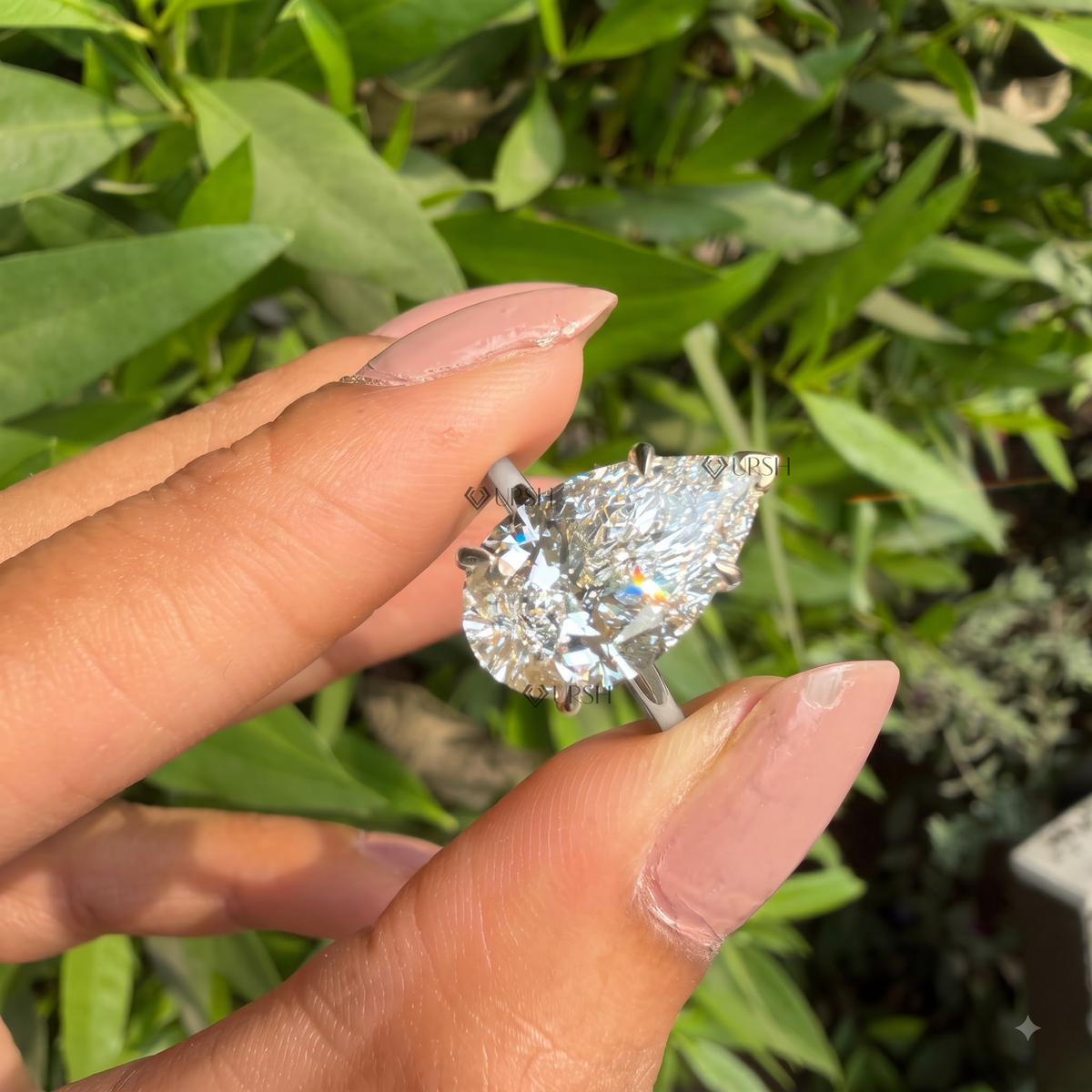 Daylight angle view of giant pear diamond solitaire ring worn on hand showcasing high-profile brilliance
