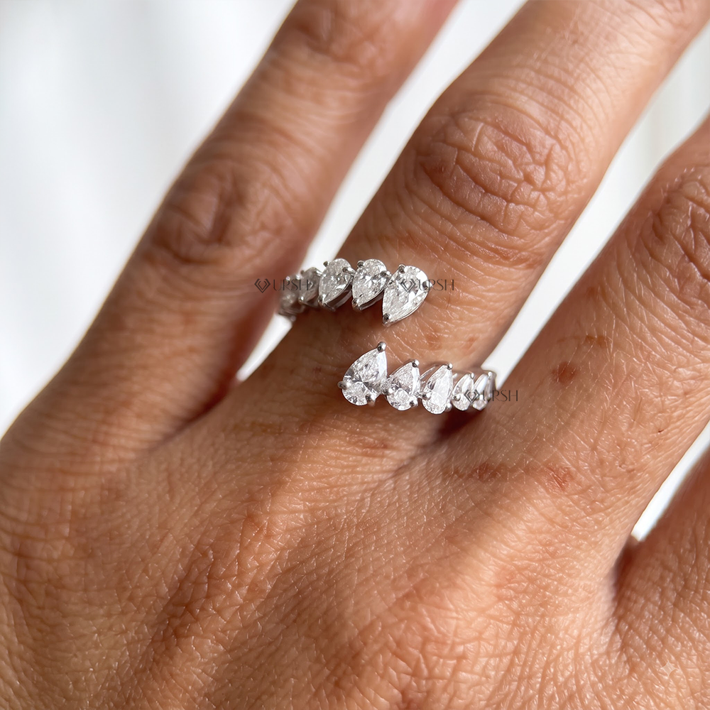 Graduated pear diamond open wrap band catching natural daylight across ring finger