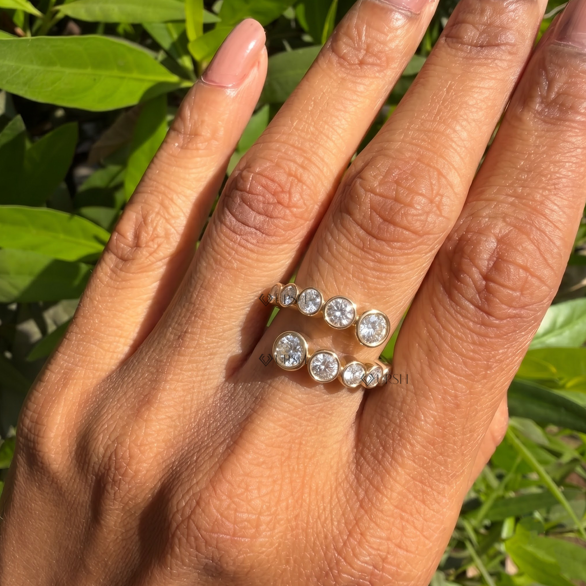 Yellow gold graduated bezel bypass ring styled gracefully on finger in natural daylight
