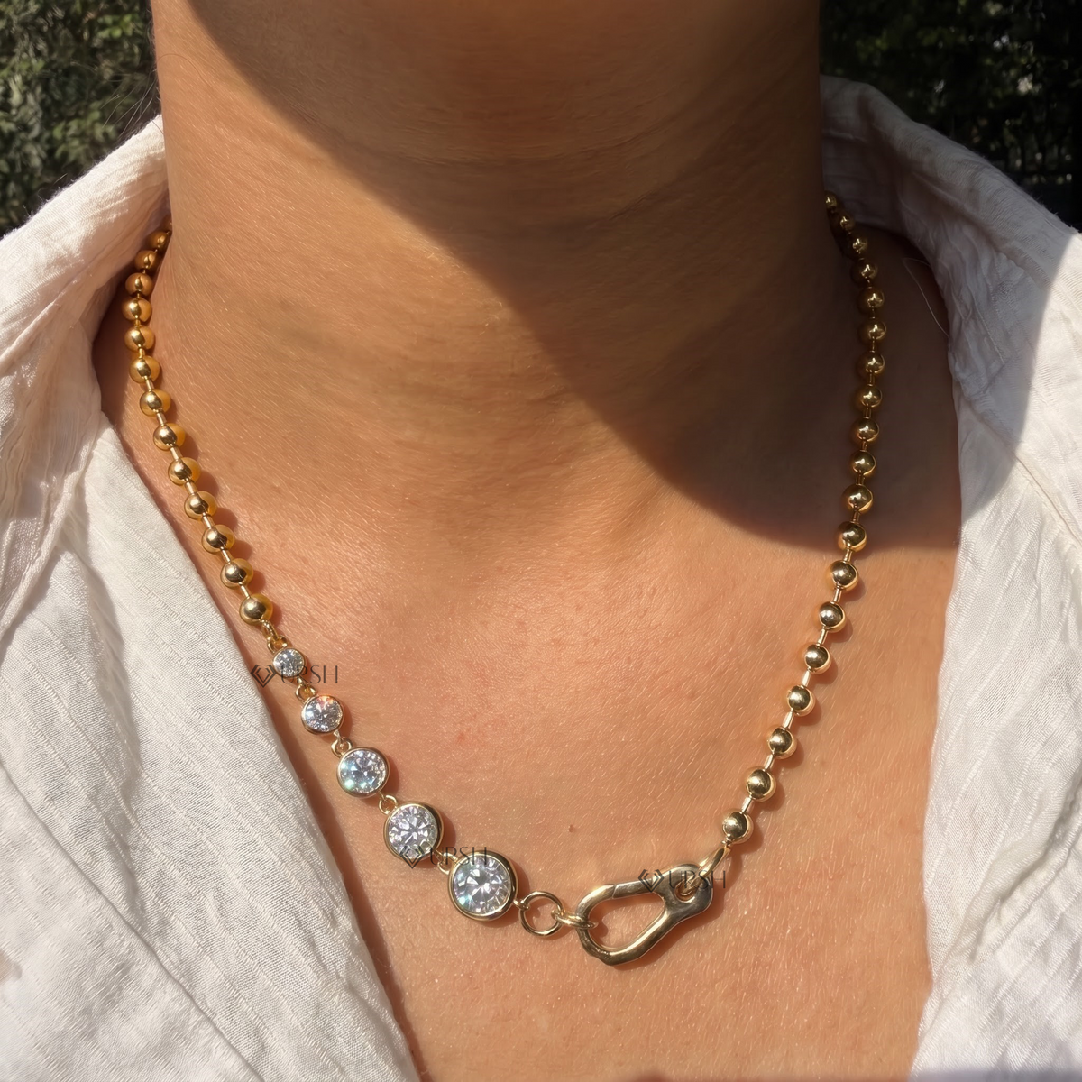 Yellow gold graduated bezel diamond ball bead chain necklace styled gracefully on neck in natural daylight