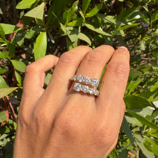 Yellow gold graduated prong bypass ring styled gracefully on finger in natural daylight