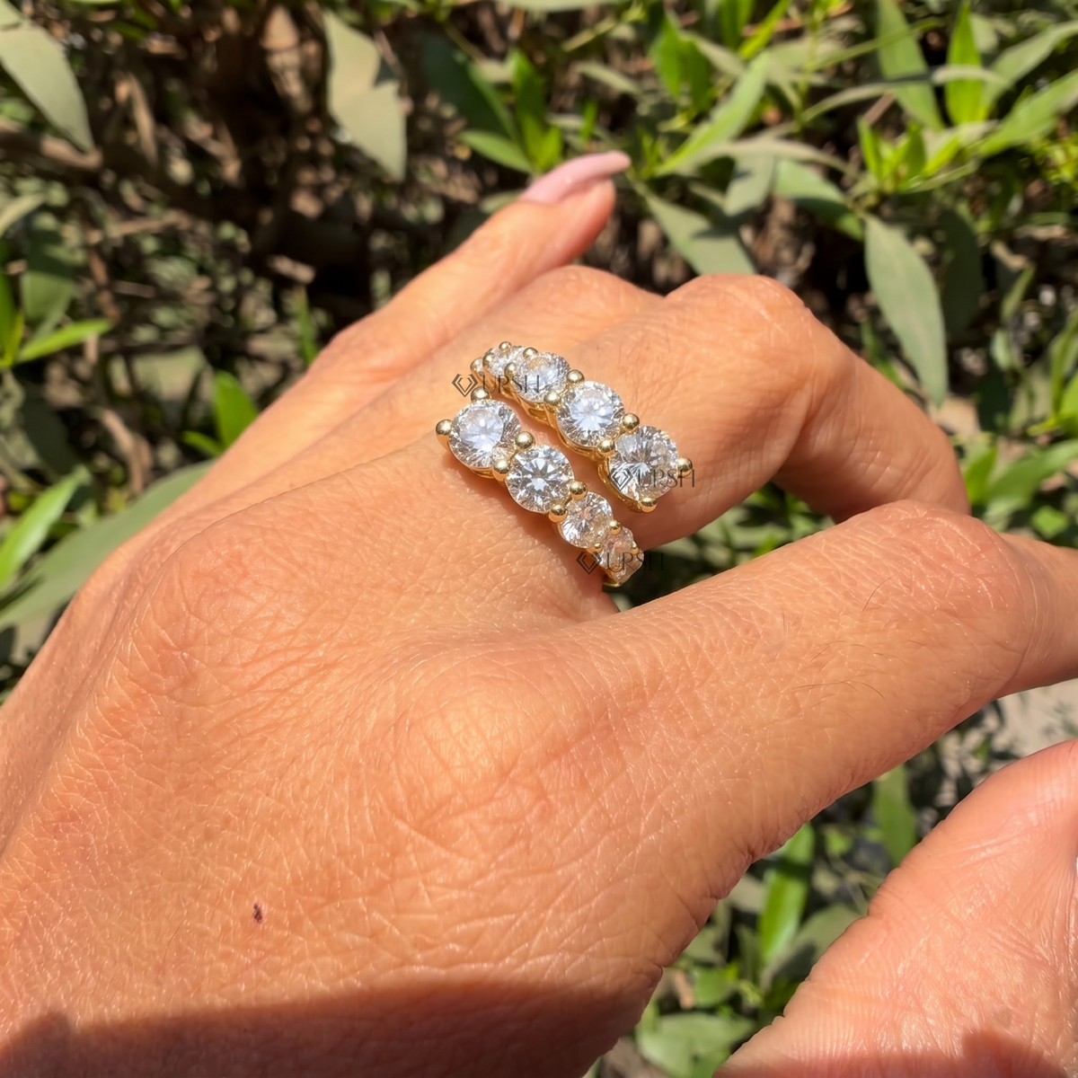 yellow gold graduated round diamond bypass wrap ring worn against natural garden greenery