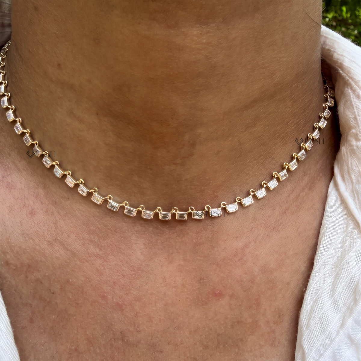 Daylight macro view of yellow gold horizontal emerald cut diamond bezel settings resting along collarbone